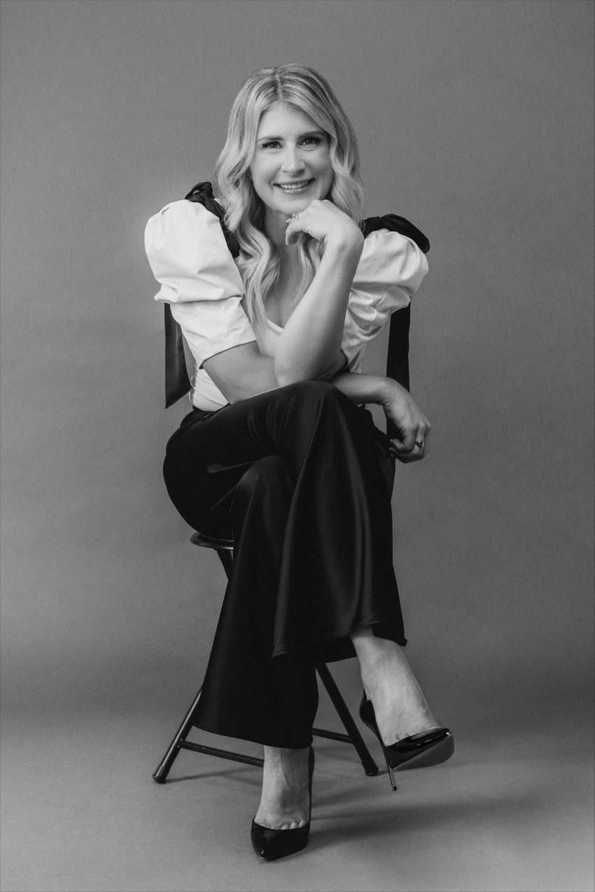 A black and white image of a smiling woman sitting down facing the camera
